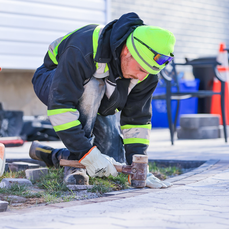 man installing pavers with a hammer